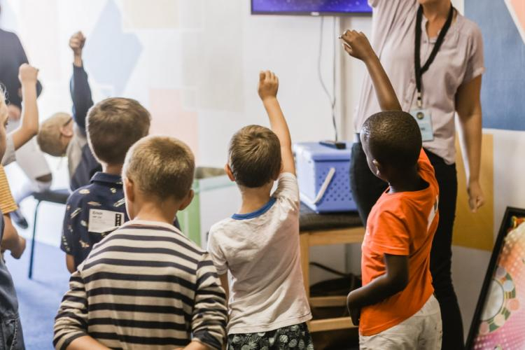 children with their hands up in a classroom