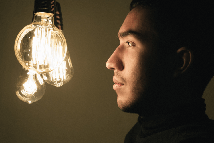 Man looking at a neon lightbulb